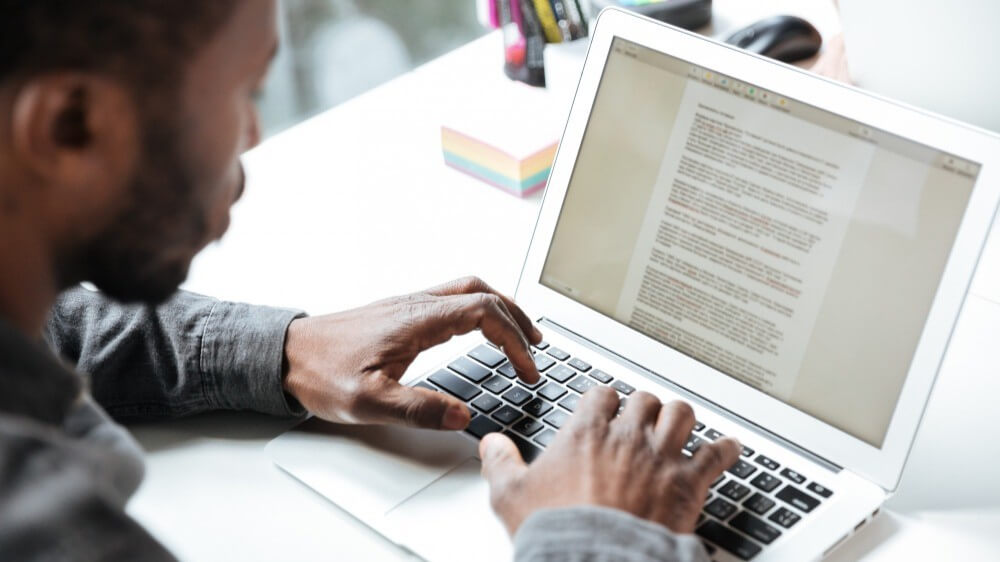 Homme travaillant sur un ordinateur portable en rédigeant du contenu digital, illustrant le copywriting au Maroc